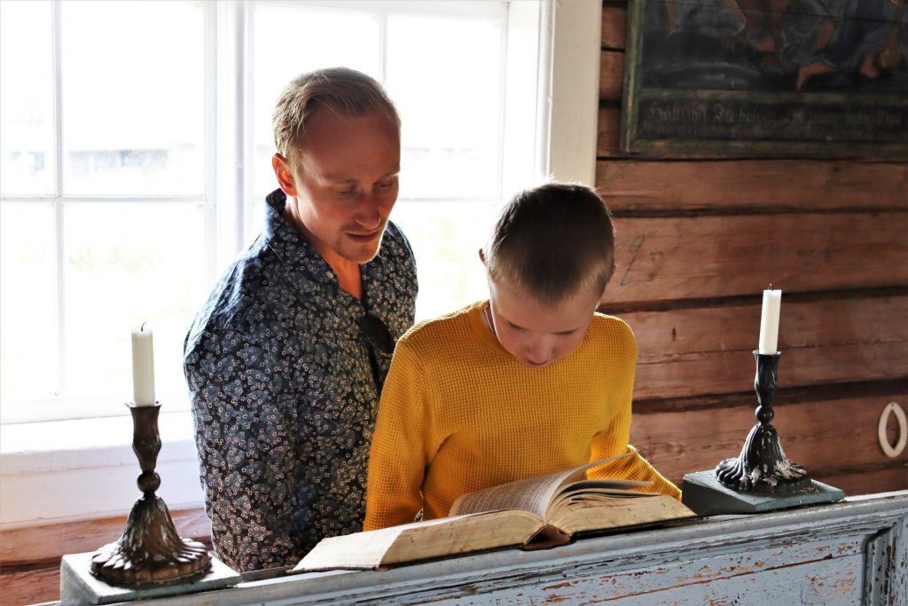 Isä ja poika lukemassa raamattua Tankarin kirkossa.